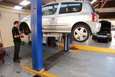 Paul works on a car on the vertical lift. 